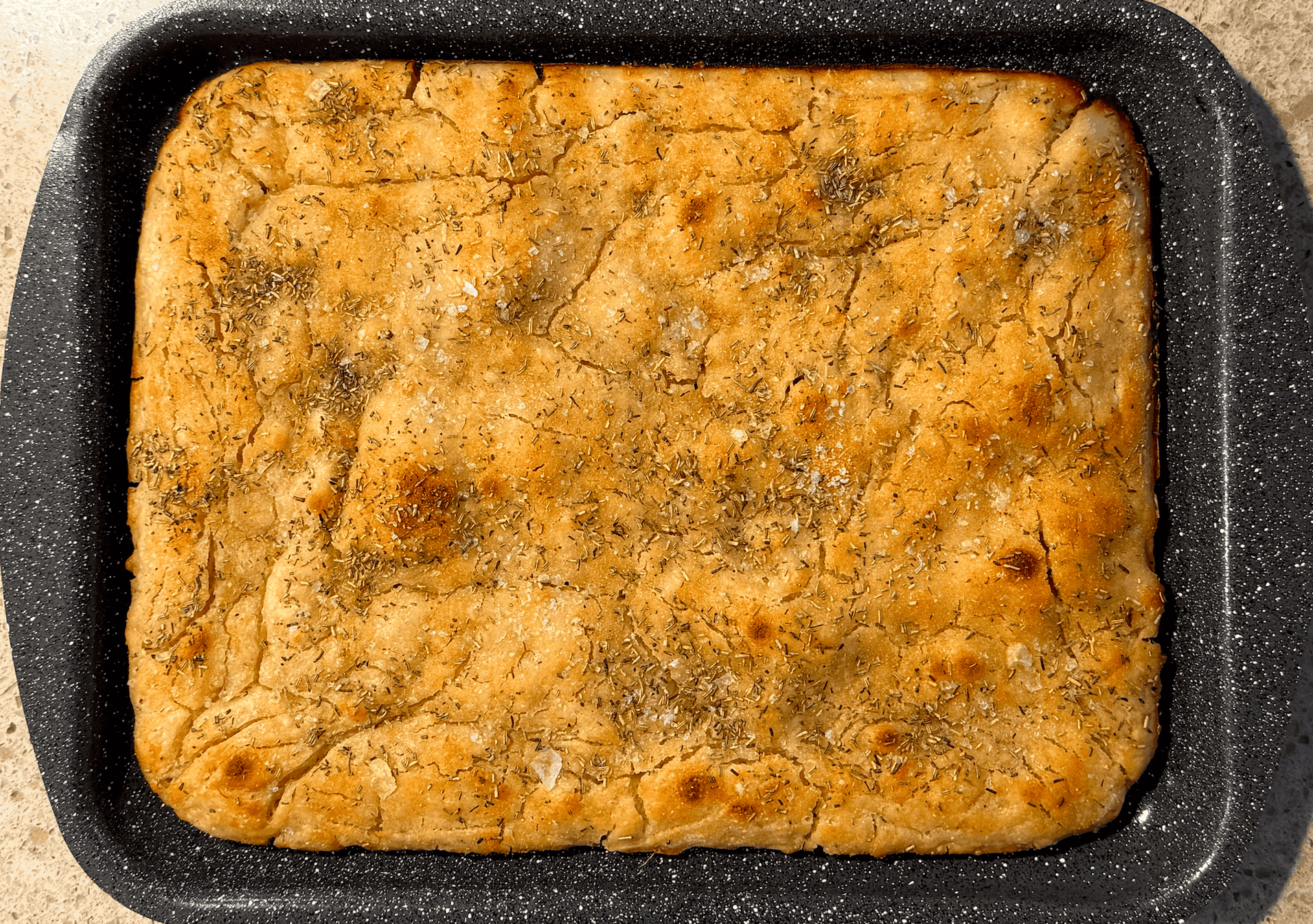 Top-down view of vegan sourdough dough after an 8-hour rise in a mixing bowl, drizzled with olive oil, ready for baking